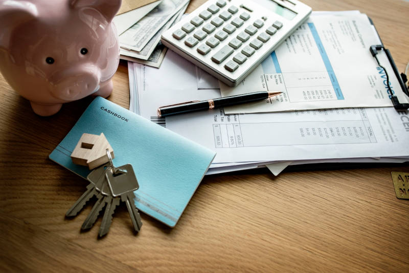 piggy bank, house keys, calculator, and financial documents